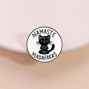 Funny black cat meditating enamel pin with Namaste Madafakas text on pink stand