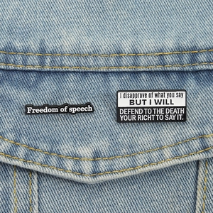 Set di spille smaltate con scritta Freedom of Speech appuntate su una giacca di jeans