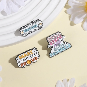 Detailansicht von Emaille-Anstecknadeln mit Motivationssprüchen in zarten Pastelltönen
