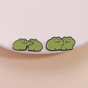 Set di due simpatiche spille in smalto a forma di rana verde su un piatto di ceramica