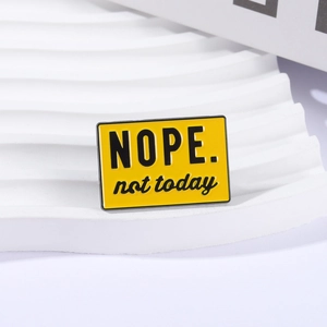 Close-up of yellow enamel badge with Nope not today text on a white wavy stand