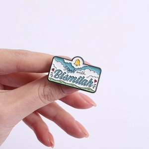 Détail de la broche émaillée bleue avec texte Start with Bismillah et charms mignons