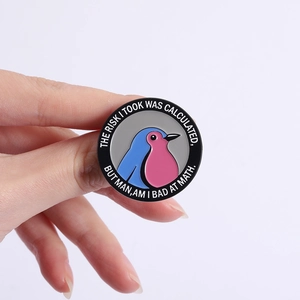 Pin's rond émaillé avec oiseau et citation drôle tenu sur fond blanc épuré