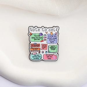 Detalle del pin esmaltado con 'Note to self' y frases motivadoras en color
