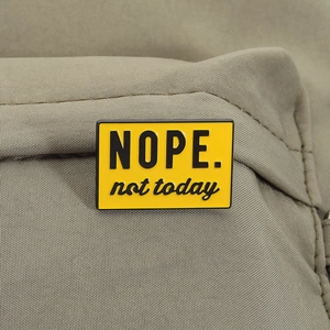 Humorous 'NOPE. not today' yellow enamel pin badge on olive green fabric background