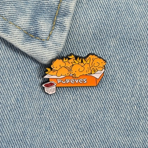 Detail of cute enamel chicken nugget dog pin attached to light blue denim jacket