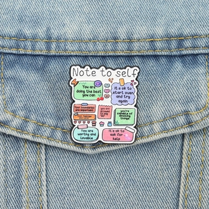 Primer plano de un pin de esmalte colorido con frases motivadoras en chaqueta vaquera