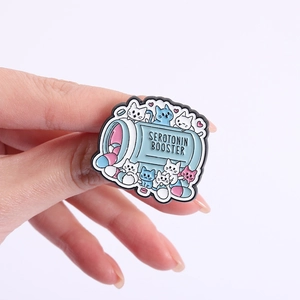 Handheld serotonin booster enamel pin featuring cute cats and colorful pills in a bottle