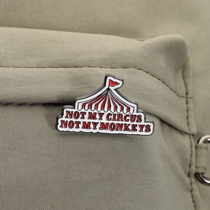 Detailed view of Not My Circus enamel pin attached to a green canvas backpack