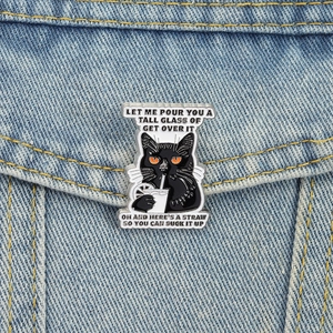 Detail of funny cartoon black cat enamel pin with quotes on blue denim jacket pocket