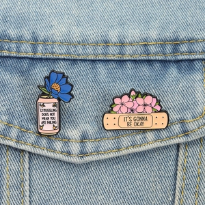 Pins émaillés fleurs sur veste en jean avec citations et motifs floraux