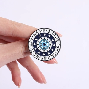 Detail van de blauwe emaille autisme speld met harttextuur en de gegraveerde tekst