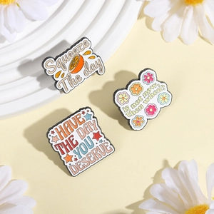 Three motivational enamel pins including Squeeze The Day orange design on a pastel background