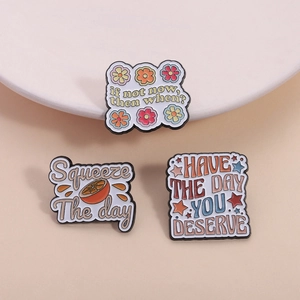 Set mit Emaille-Anstecknadeln mit Orangen- und Blumendesigns und Motivationssprüchen