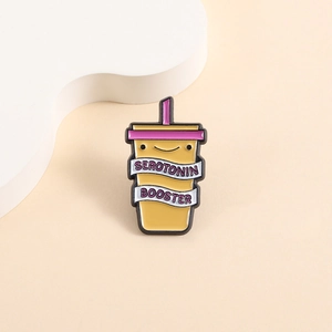 Macro detail of enamel brooch showing Serotonin Booster text and yellow cup design