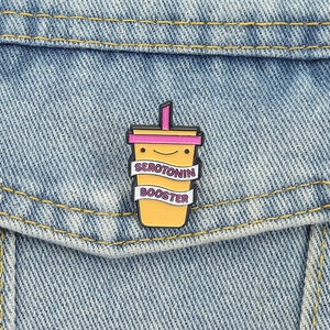 Detail of Serotonin Booster enamel pin with cartoon milk tea design on denim jacket