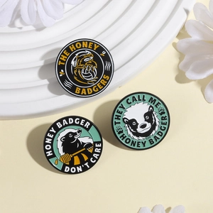 Détail de trois pin's en émail avec motif de ratel et slogans amusants en gros plan