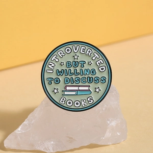 Detailed macro view of mint green enamel brooch featuring book-themed typography