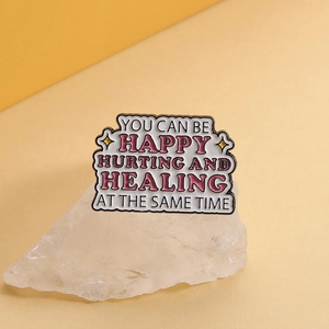 Macro shot of quote enamel pin on crystals with hurting and healing message