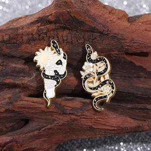 Detail of enamel pins featuring a white skeletal hand with a gold sun and a black snake