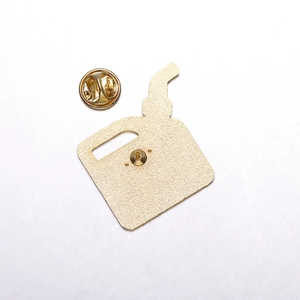 Detail of creative red paint bucket metal pin showing golden backing and butterfly clutch