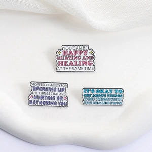 Three-piece mental health enamel pins set with healing quotes on white fabric background