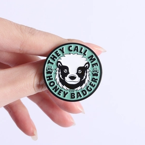 Round honey badger enamel pin with 'They Call Me The Honey Badger' slogan on mint base