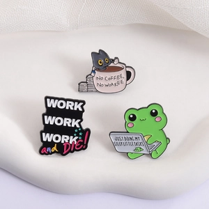 Three cartoon enamel pins featuring a cat in a coffee cup and a frog working at a computer