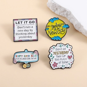 Set of four inspirational colorful enamel pins with motivational slogans on beige background