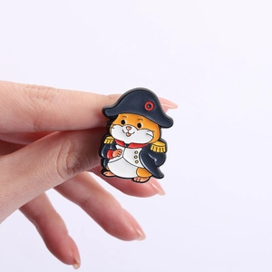 Detail of Napoleon hamster enamel pin badge with navy blue coat held by a hand
