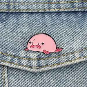Nahaufnahme einer rosa Blobfisch-Emaille-Anstecknadel auf blauem Denim-Stoff