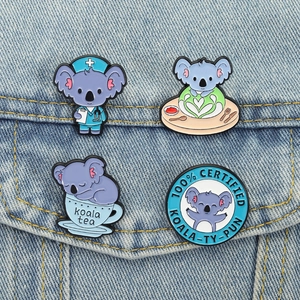 Detail of four koala enamel pins styled on a denim jacket pocket as decorative accessories