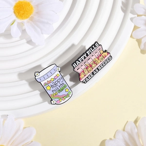 Detail of happy pills and dog schedule enamel pins on a white decorative display
