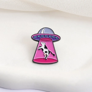 UFO kidnapping cow enamel pin with colorful purple and pink cartoon alien design