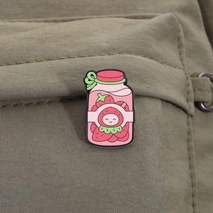 Macro shot of a cute strawberry canned drink enamel pin on a green canvas bag strap