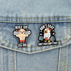 Nahaufnahme von Emaille-Pins mit Muskel-Mops und Ente auf blauem Denim-Hintergrund