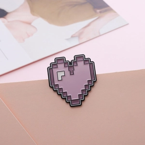 Macro shot of purple pixel heart enamel pin on light pink cardstock background