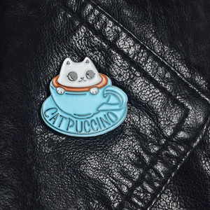 Detailed close-up of a Catpuccino enamel cat pin on a premium black leather background