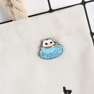 Cartoon white cat in blue coffee cup enamel pin badge on a white canvas bag