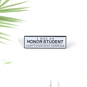 Humorous enamel pin featuring I WAS AN HONOR STUDENT slogan on a white background