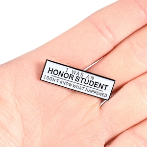 Minimalist enamel lapel pin with 'I WAS AN HONOR STUDENT' text held in hand
