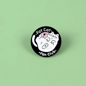 Detail of round Fat Cat Fan Club enamel pin with cute cartoon cat on black base