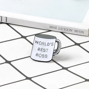 Detail of enamel coffee cup brooch featuring World's Best Boss text on white grid backdrop