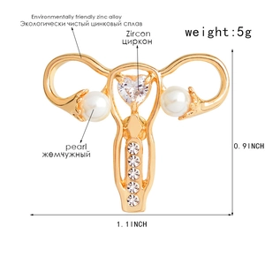 Uterus-shaped alloy brooch with heart zircon and pearls on white background