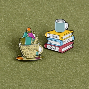 Détail de pin's créatifs en émail représentant des tasses de café et livres sur fond vert