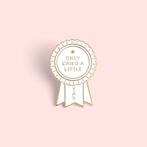 White enamel medal brooch featuring 'ONLY CRIED A LITTLE' text on light pink background