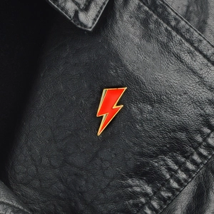 Creative red lightning bolt enamel brooch pin with gold metal edges on black leather jacket