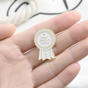 Enamel medal brooch with gold edges and Yay Only Cried A Little text in hand