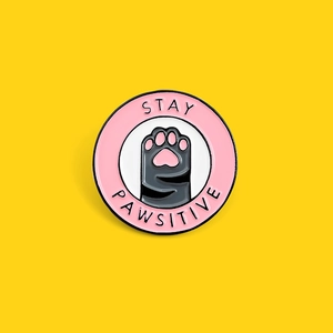 Detailed view of the Stay Pawsitive enamel pin featuring a pink heart cat paw motif