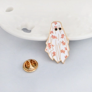 Ghost enamel pin with pink floral sheet and black sunglasses on a white ceramic dish